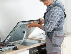 Appliance repair technician installing a built-in cooktop in Sacramento, CA