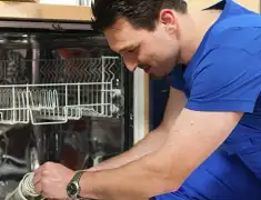 Dishwasher repair technician inspecting and servicing an open dishwasher in Sacramento, CA