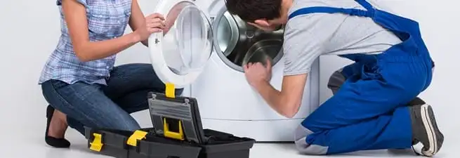 Washer repair technician inspecting a front-load washing machine with tools in Sacramento, CA