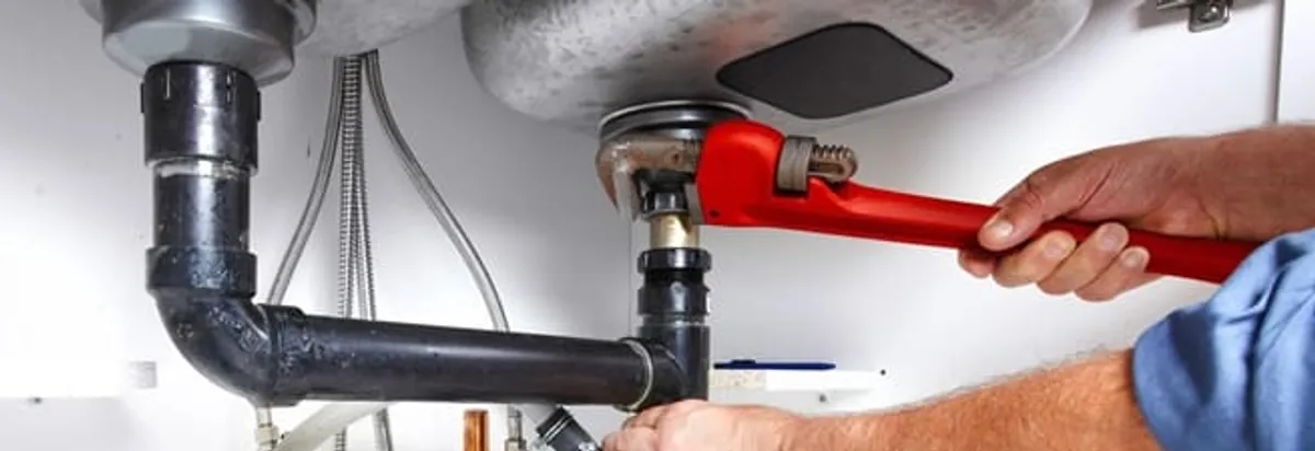 Garbage disposal repair technician tightening the sink drain and disposal connection in Sacramento, CA