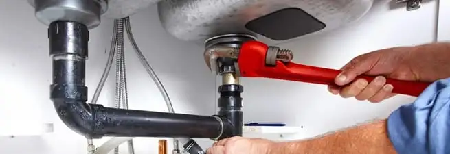 Garbage disposal repair technician tightening the sink drain and disposal connection in Sacramento, CA