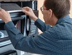 Appliance repair technician replacing a microwave vent filter in Sacramento, CA