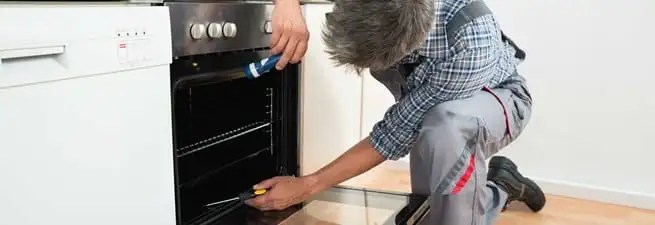 Oven repair technician inspecting and servicing an electric oven in Sacramento, CA