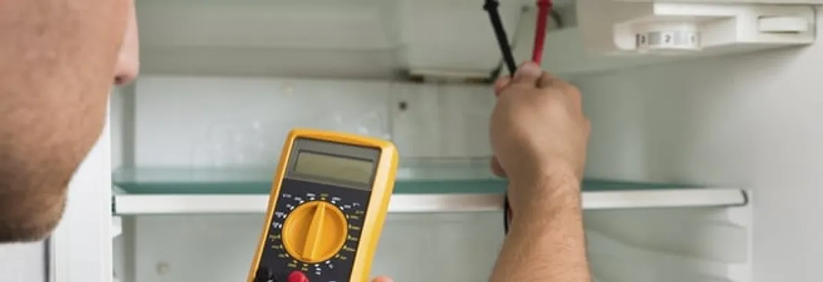 Refrigerator repair technician testing electrical components with a multimeter in Sacramento, CA