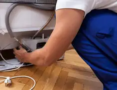 Appliance repair technician fixing refrigerator water line and connections in Sacramento, CA