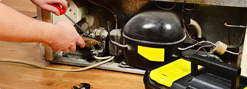 Refrigerator repair technician fixing the compressor and wiring in Sacramento, CA