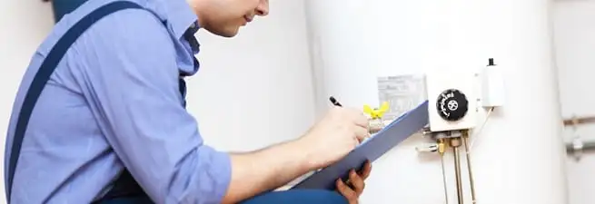 Water heater repair technician inspecting the unit and recording service notes in Sacramento, CA